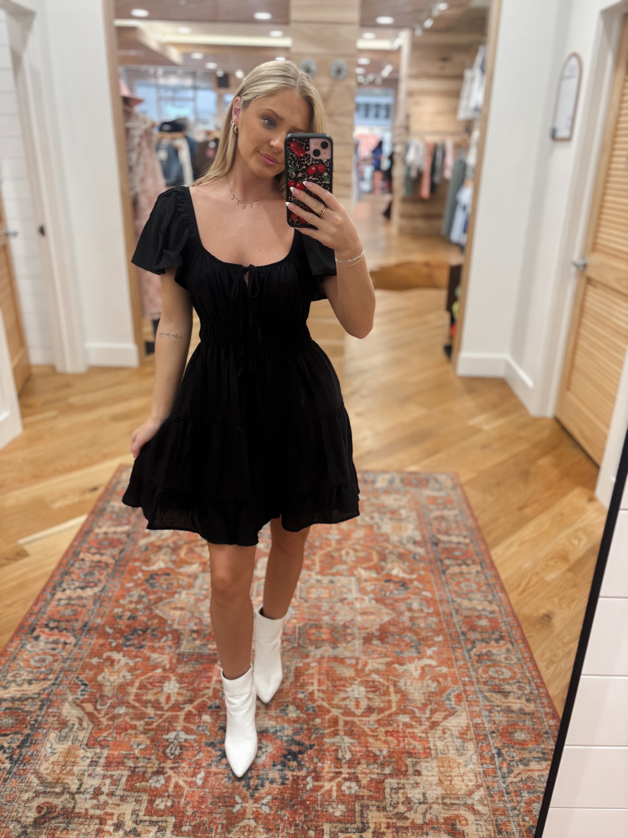 This Dark Romance Black Mini Dress features a scoop neckline, short batwing sleeves, and a front tie strap detail. The non-functional double waist tie detail and elasticized waist provide a flattering fit, while the tiered lining adds texture. Boutique style Ashland, Kentucky 