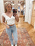 The Kiki White Top features a V neckline, short elastic ruched sleeves, and a front lace with ribbon bow detail. Its cropped design, solid color, and woven fabrication make it a stylish and versatile addition to any wardrobe. Made of 61% rayon, 36% nylon, and 3% spandex for a comfortable fit. Boutique style Ashland, Kentucky 