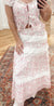 Sweet and feminine, this tiered maxi skirt showcases a soft pink and white ditsy rose print with delicate lace inset detailing. The flowing silhouette and romantic layers create a vintage-inspired look that’s perfect for garden parties or summer strolls. Pair it with the matching puff sleeve crop top featuring a ruched front and bow tie detail for the complete romantic set.